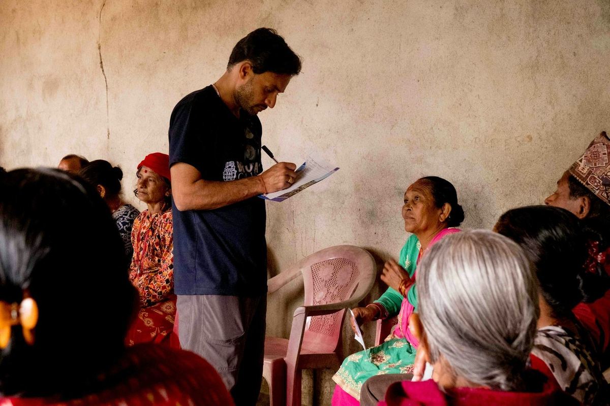 A researcher takes notes on a clipboard while talking with a group of women